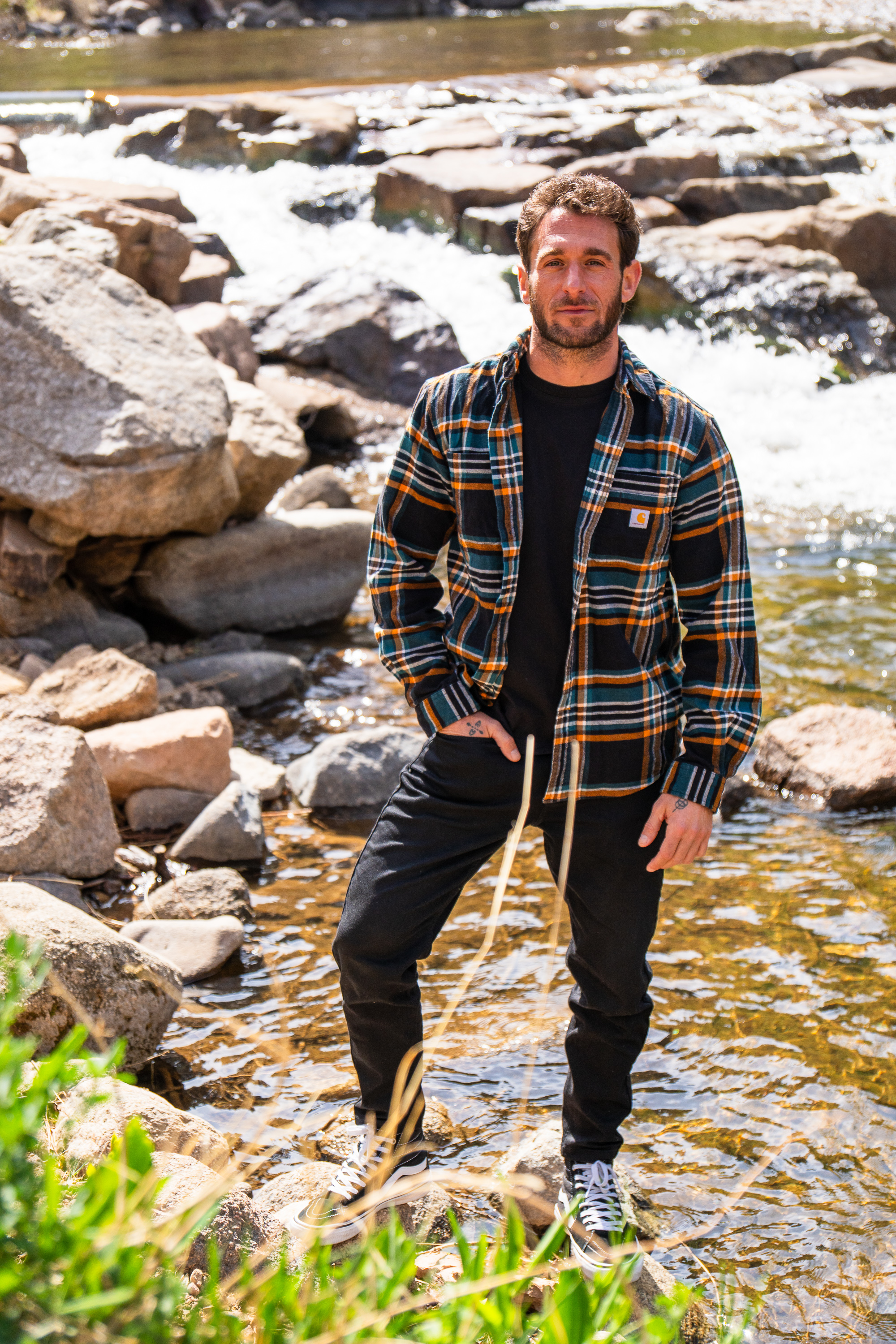 Nicholas Balsamo standing on rocks in a sunlit forest creek